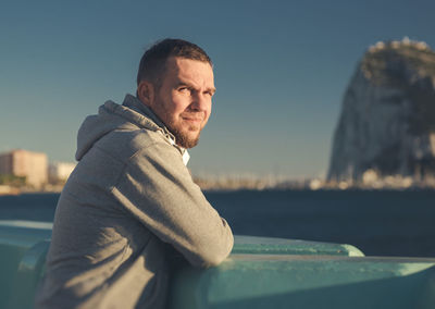 Portrait of handsome man leaning on railing at gibraltar