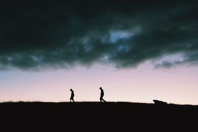 Silhouette people standing on landscape against sky during sunset