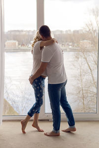 Pregnant woman standing with her husband next to the window