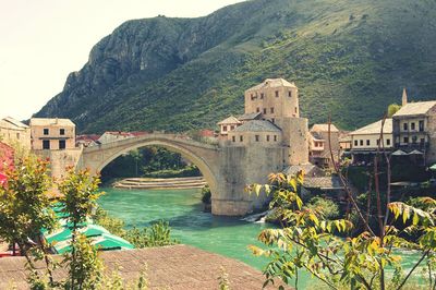 Stari most bridge over river by grassy mountain