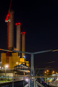 Low angle view of illuminated factory against sky at night