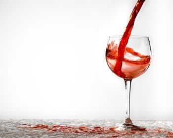 Close-up of red wine in glass against white background