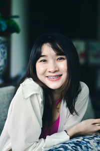 Portrait of young woman sitting on bed at home