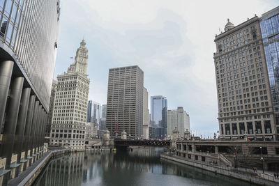 Bridge over river amidst buildings against sky in city