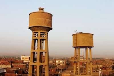 Old tower and buildings in city against clear sky