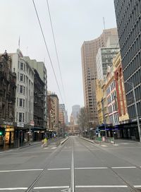 Road amidst buildings in city against sky