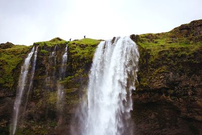 Low angle view of waterfall against sky