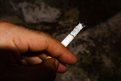 Close-up of hand holding cigarette