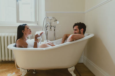 Side view of couple sitting in bathtub