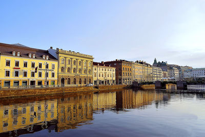 Buildings by canal against sky in city
