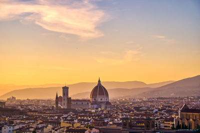 Illuminated buildings in city against sky during sunset