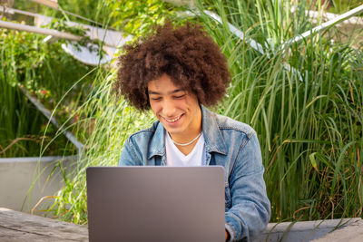 Portrait of woman using laptop while sitting on field