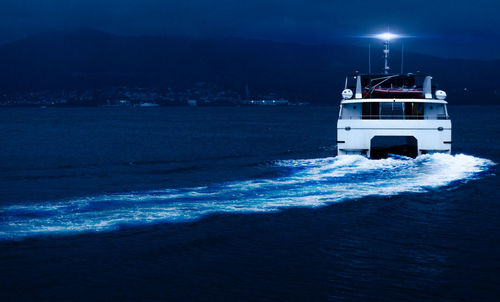 Boat sailing in sea against sky at night