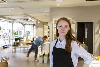 Portrait of confident owner standing against customer in boutique