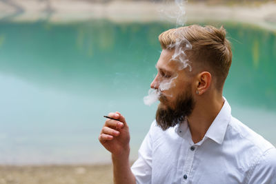 Handsome serious guy, young thoughtful man smokes, heating tobacco products