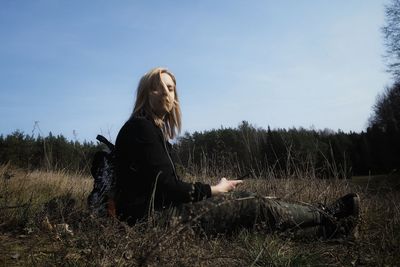 Side view of woman sitting on field