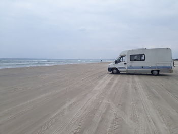 Van on beach against sky