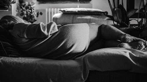 Low section of woman sitting on sofa at home