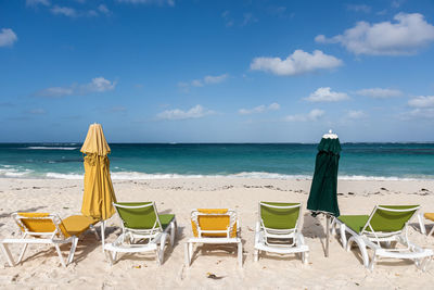 Deck chairs on beach against sky