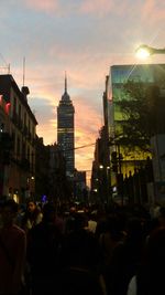 People walking on city street at sunset