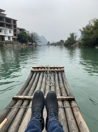 Low section of man on boat in lake against sky