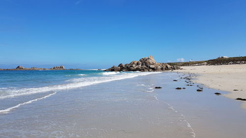 Scenic view of beach against clear blue sky