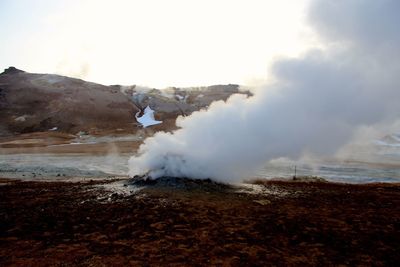 Smoke emitting from volcanic landscape against sky