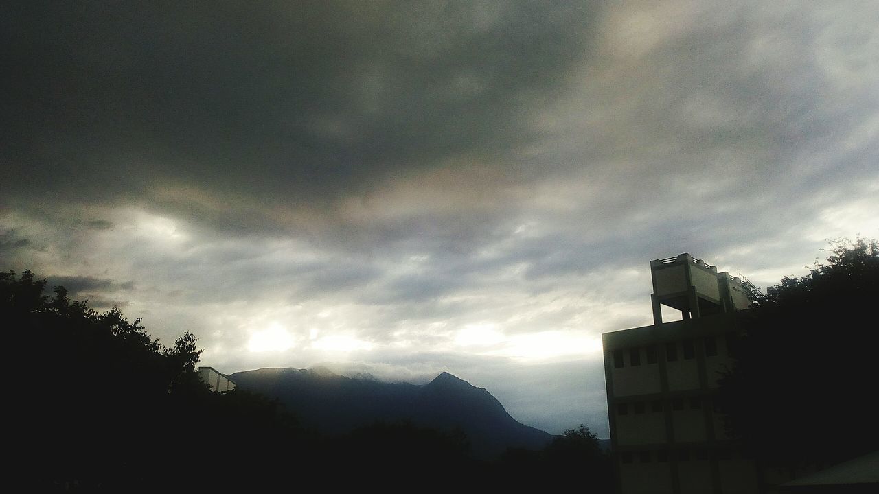 LOW ANGLE VIEW OF STORM CLOUDS OVER SILHOUETTE OF BUILDING