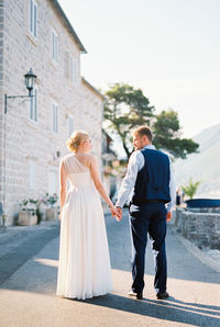 Rear view of couple walking on street in city