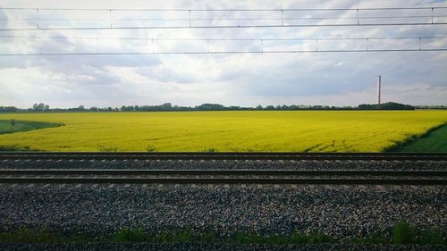 View of field against cloudy sky