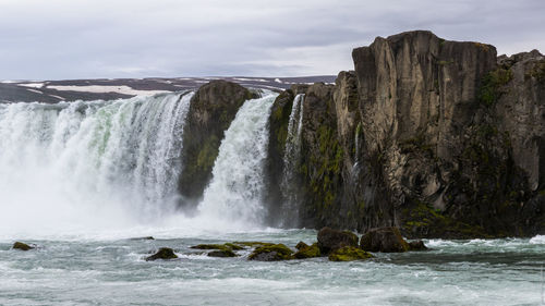 Low angle view of godafoss against cloudy sky