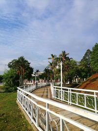 Bridge by palm trees against sky