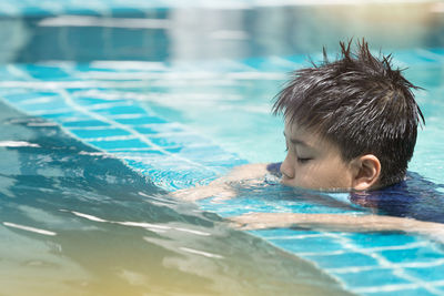 Boy happy swimming in a pool. children swimming and playing in water.