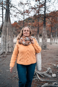 Portrait of woman standing by tree in forest