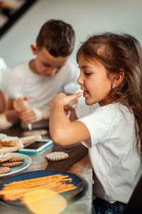 Cute girl sitting by cookies in kitchen