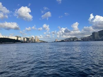 Scenic view of sea by city buildings against sky