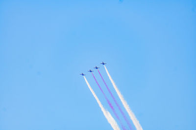 Low angle view of airshow against blue sky