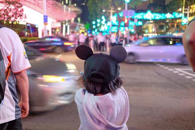 Rear view of man on illuminated street at night