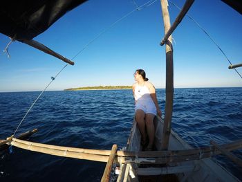 Young woman on boat in sea against sky