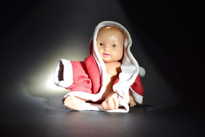 Portrait of cute baby girl sitting against black background