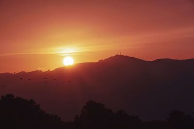 Scenic view of silhouette mountains against orange sky