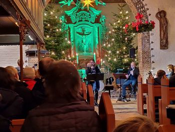 Rear view of people sitting on illuminated christmas tree