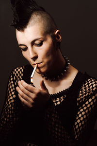 Portrait of young woman holding camera over black background