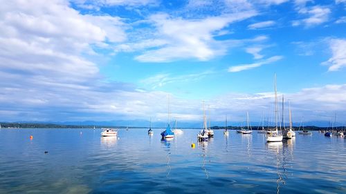 Sailboats moored in sea against sky