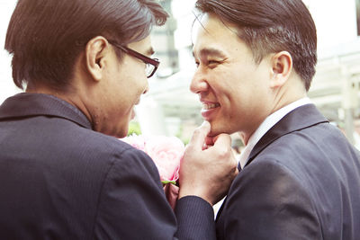 Close-up of gay couple smiling during wedding ceremony