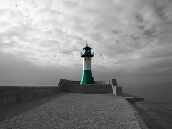 Lighthouse by sea against sky