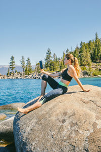 Young woman sitting by lake tahoe reading a kindle book during the day