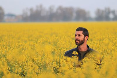 Portrait of man with yellow flowers in field