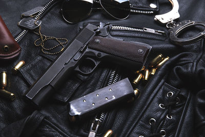 Directly above shot of handgun and bullets on leather jacket