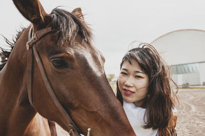 Close-up portrait of young woman with horse on land against sky